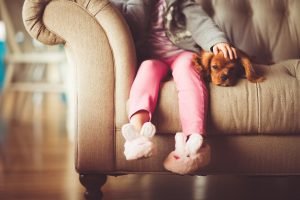 A child and a pet sitting on a couch after moving from South Carolina.