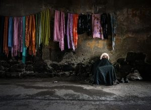 Woman on the street, with clothes hanging behind her.