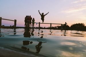 This silhouette of a person jumping into the river near a dock is resting after moving during the summer.