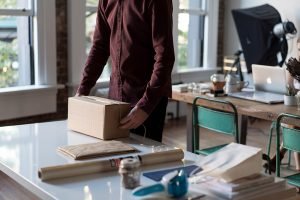 A man packing a box with ducktape, rope and packing paper