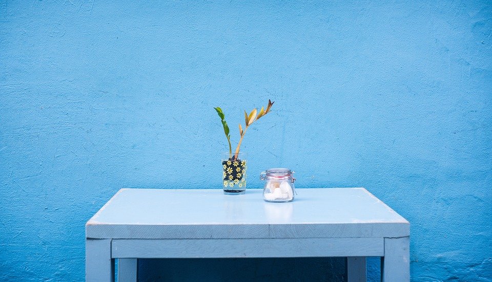 A blue desk in front of a blue wall.