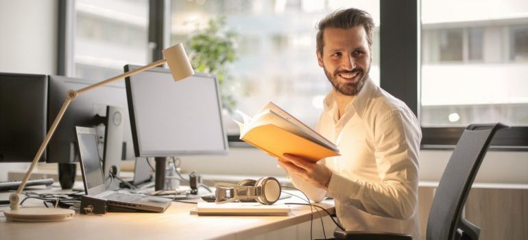 A man holding notes at his desk and smiling at work.