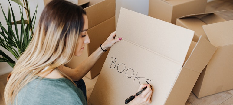 Woman labeling a box for moving before the best cross country movers Atlanta arrive