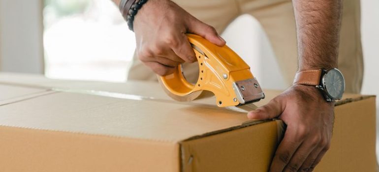 man-taping-carrying-box-with-scotch