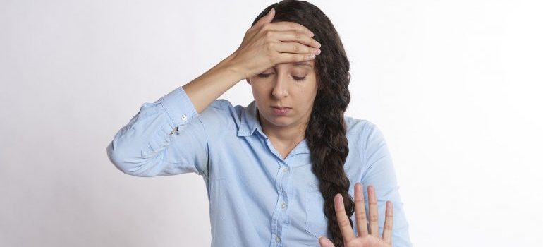 A woman holding her forehead due to stress, instead of hiring the best cross country movers in South Burlington.