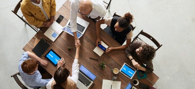 An overhead view of business professionals working at a single table, looking for best cross country movers in Stamford.