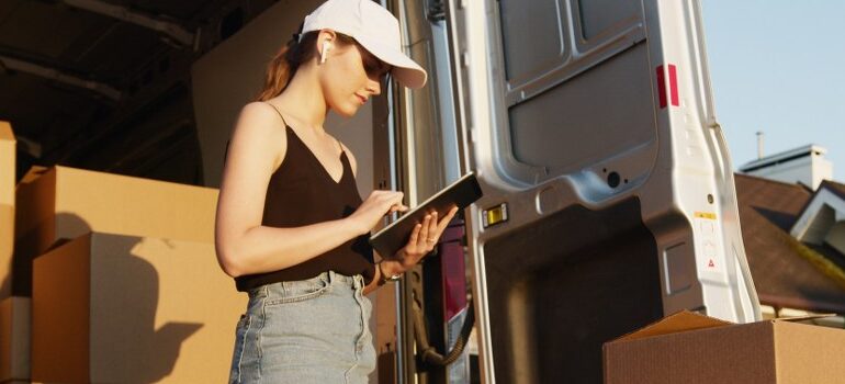 woman creating a list, moving boxes and a van behind