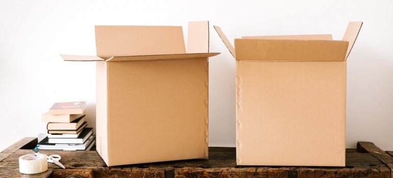 Two boxes made out of cardboard sitting on a wooden desk.