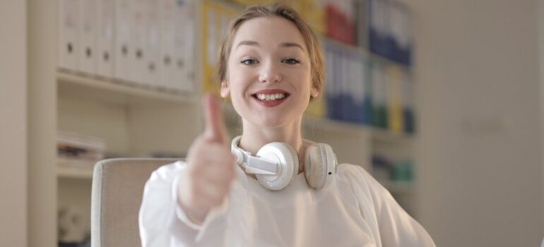woman with a headset, smiling, thumbs up