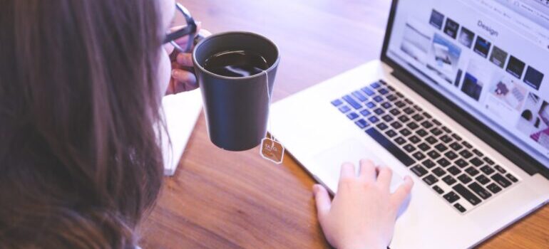 Woman holding tea and looking at the laptop