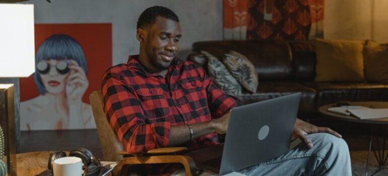 A man in a plaid shirt using laptop to find best cross country movers Topeka.