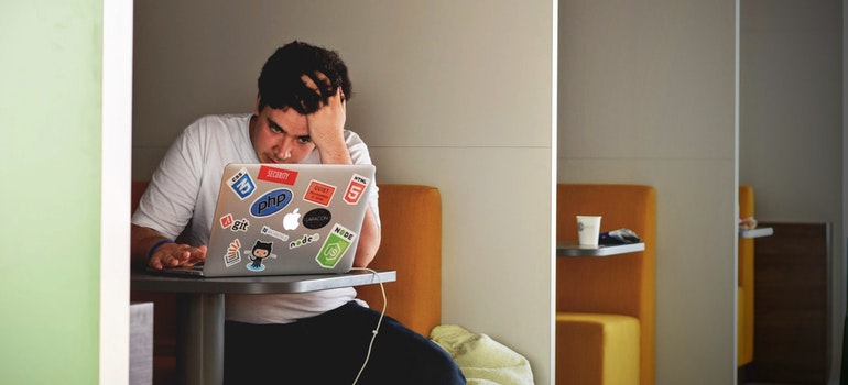 A stressed out man looking at a laptop