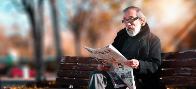 elderly man reading newspapers on a bench in the park on best places to live in Delaware 2022
