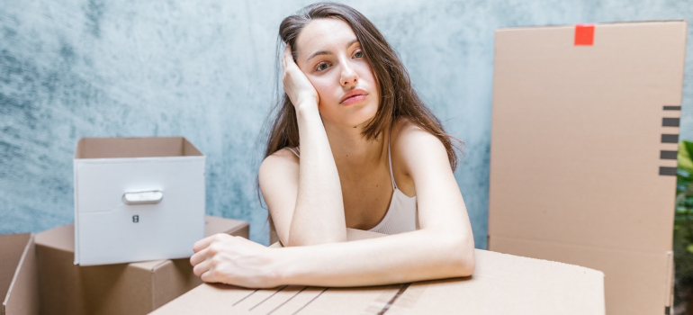 a woman leaning on a cardboard box while thinking