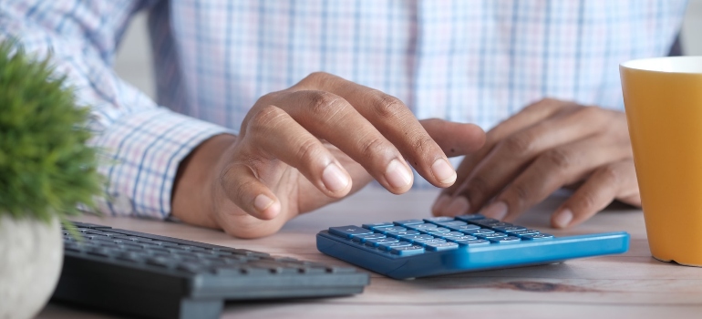 Close up of man hand using a calculator - manage moving costs when relocating cross-country.
