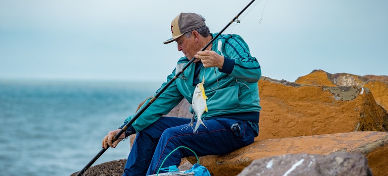 Elderly Man in a Blue Jacket Holding a Fishing Rod.