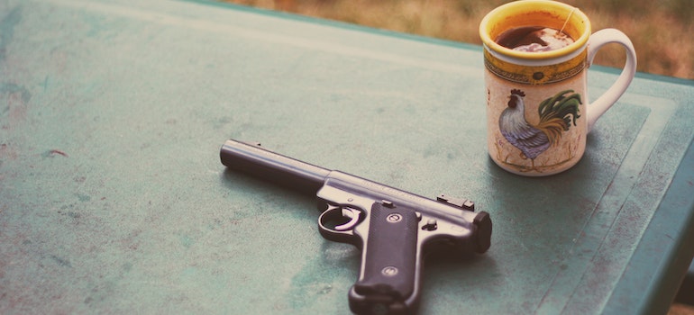 Photo of Handgun Near Mug.