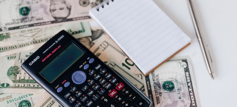 a black calculator, a notepad and a pen on a pile of money
