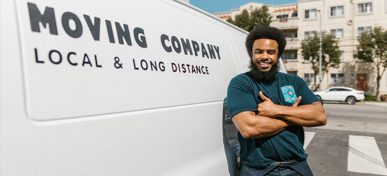 A mover employee smiling next to their van