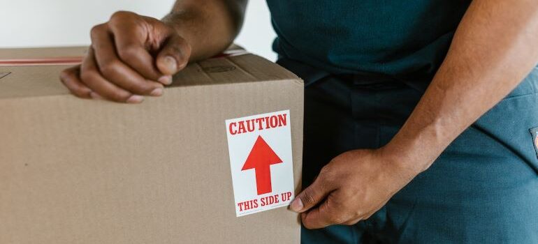 a man taping a sticker that says caution on a box