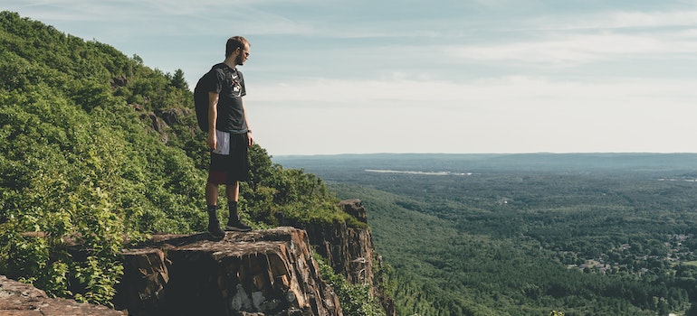 A man standing on a cliff enjoying the nature after moving from Washington to Massachusetts