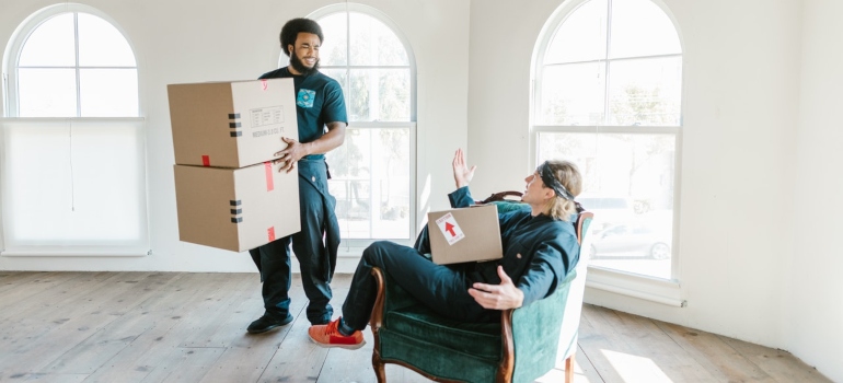 Movers carrying boxes, one standing the other one sitting