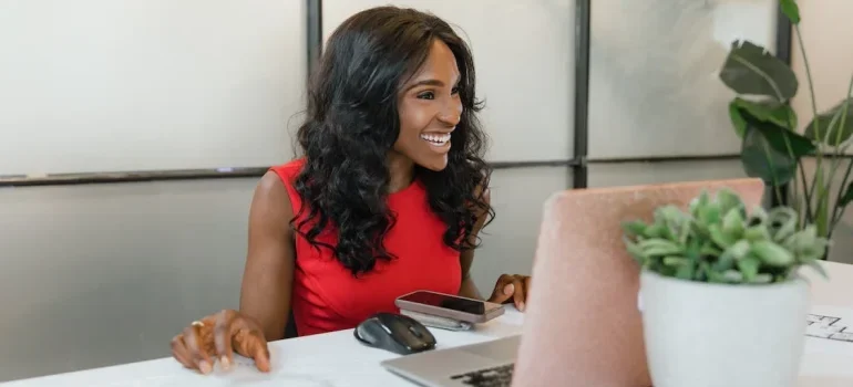 A woman sitting in front of the computer and smiling