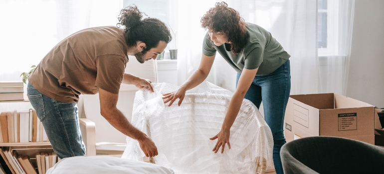 two people packing items in bubble wrap