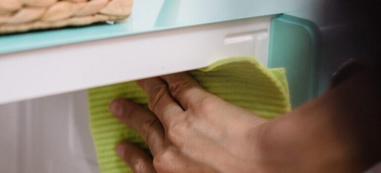 Hand holding a cleaning cloth and cleaning a microwave