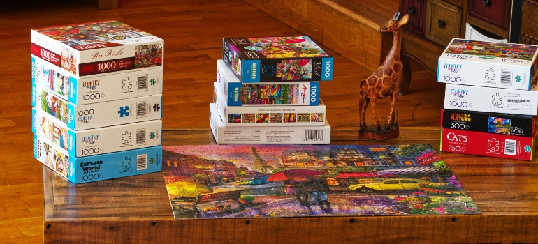 a lot of boxes with games on the wooden table and puzzle made on the table 