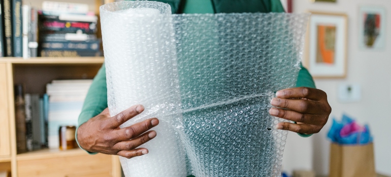 man holding a roll of bubble wrap to use for packing toys and games for a move