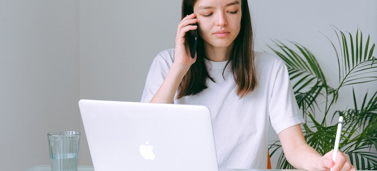 A woman using a phone and a laptop