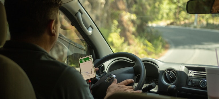a man driving while looking at a map on his smart phone