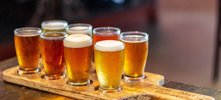 eight full glasses of beer served on a wooden cutting board