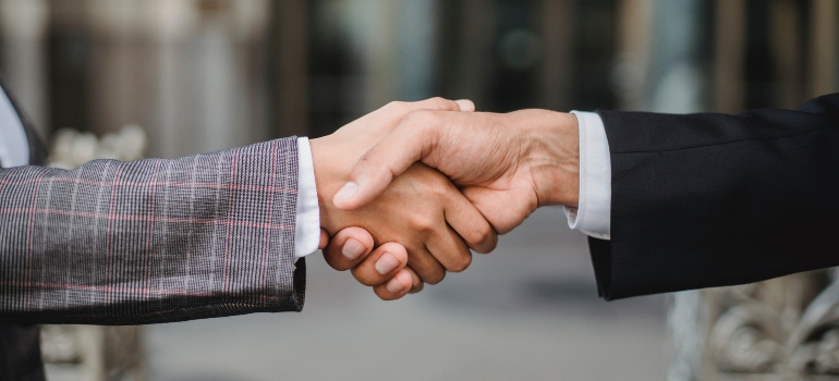 A handshake between two women in a business suit and checked grey blazer