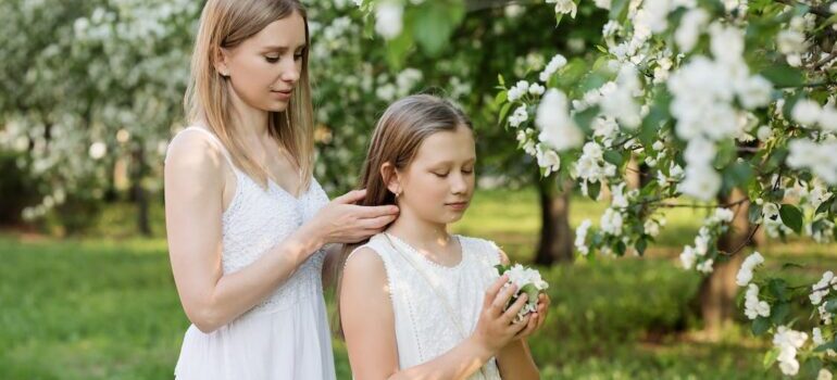 A woman fixing the little girl's hair in a garden with white blossom trees