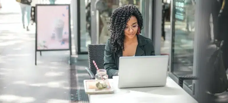 A young woman using her computer outside a cafe