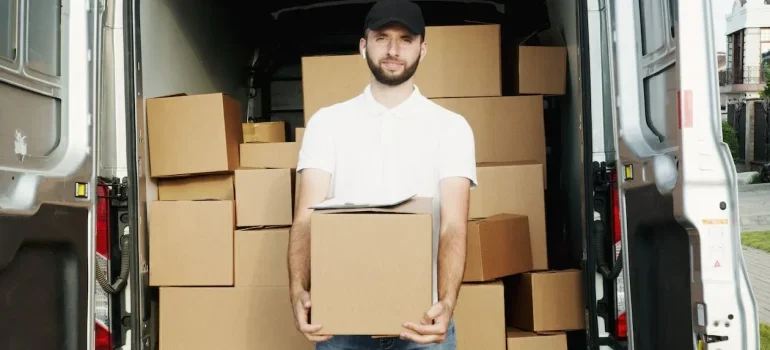 A man holding a box in front of the moving van