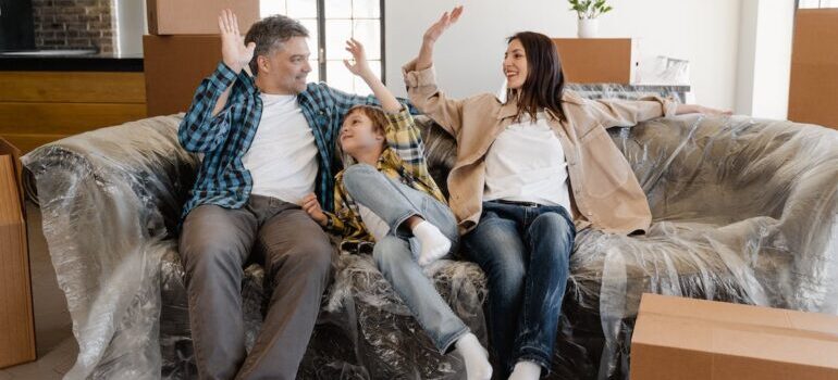 A happy family sitting on the couch covered with plastic