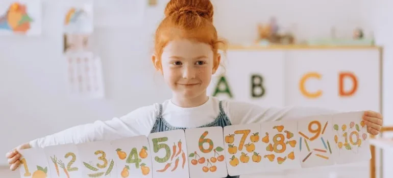 A girl in the classroom holding a paper banner with numbers