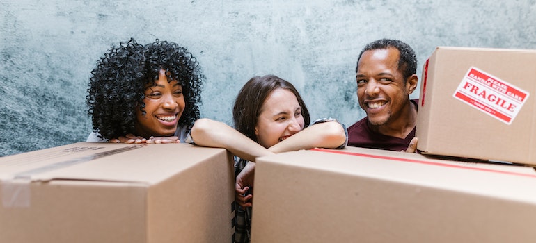 people smiling while standing behind cardboard boxes