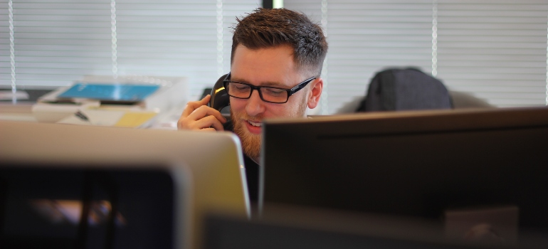 A man talking on phone behind computer screens