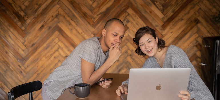 A couple looking at a Macbook smiling