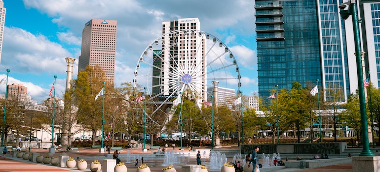 A Ferris wheel in front of a fountain and tall glass buildings in Atlanta, GA