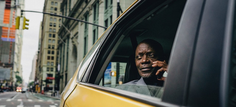 a man in a yellow taxi, talking about moving trends in NYC