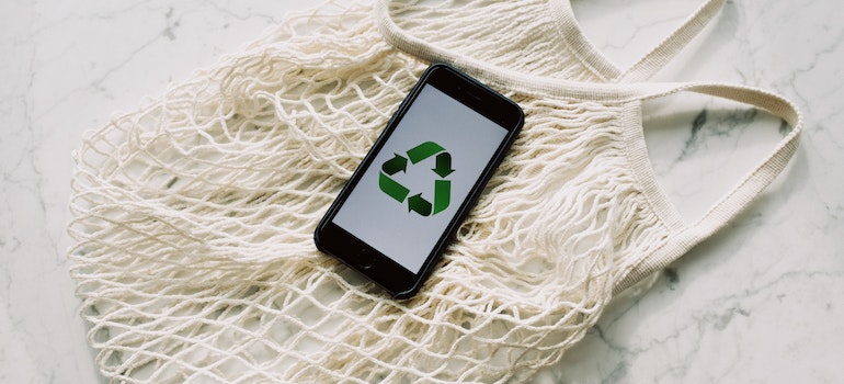 a phone with a recycle logo on a knit shopper bag