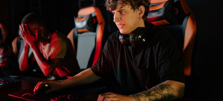 a gamer with headphones and arm tattoos playing a game