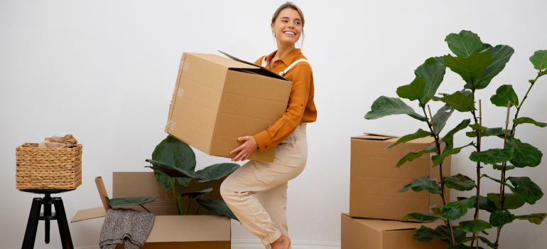 A woman smiling while holding a cardboard box in her hand