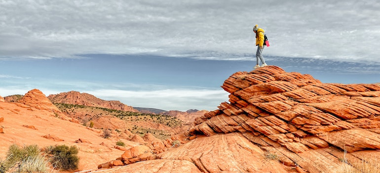 A woman in hiking gear standing on top of a red cliff in Arizona Grand Canyon