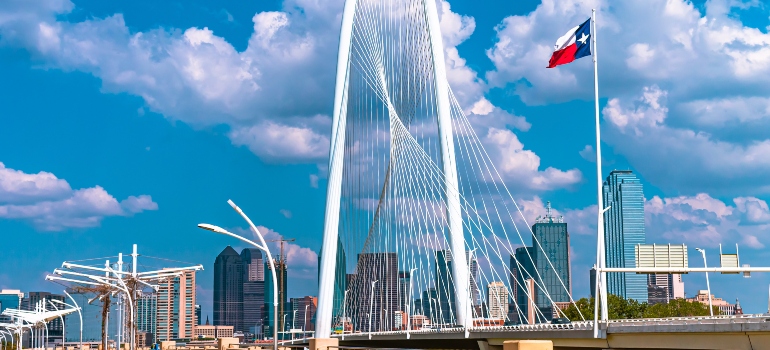 A bridge in Texas people cross when moving from Tampa to Dallas by car with a Texas flag waving in the wind